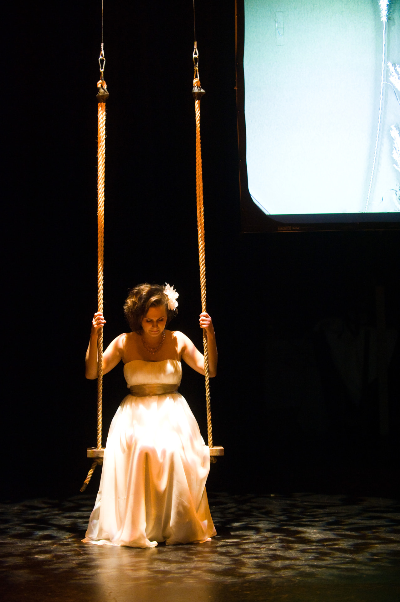 Performer on a rope swing under a focused spotlight